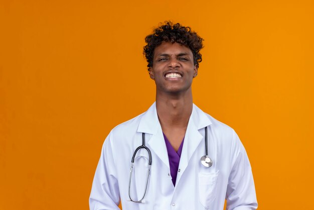 Un jeune homme à la peau foncée et aux cheveux bouclés portant un manteau blanc avec stéthoscope