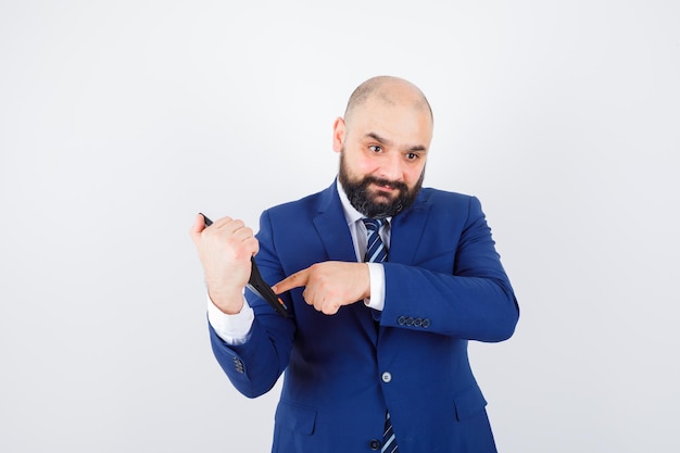 Jeune homme pointant sur la calculatrice en chemise blanche, veste et à l'air confiant. vue de face.