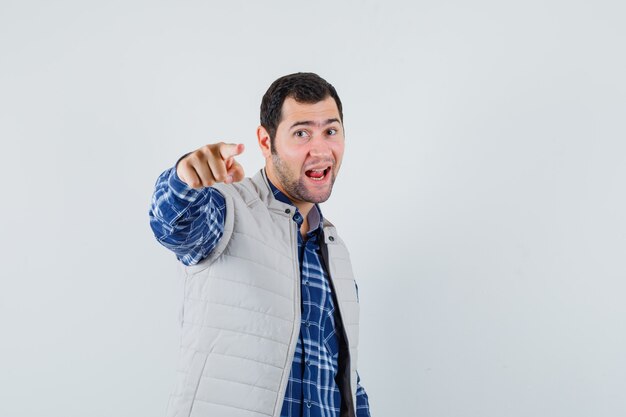 Jeune homme pointant la caméra en chemise, veste sans manches et à la recherche concentrée