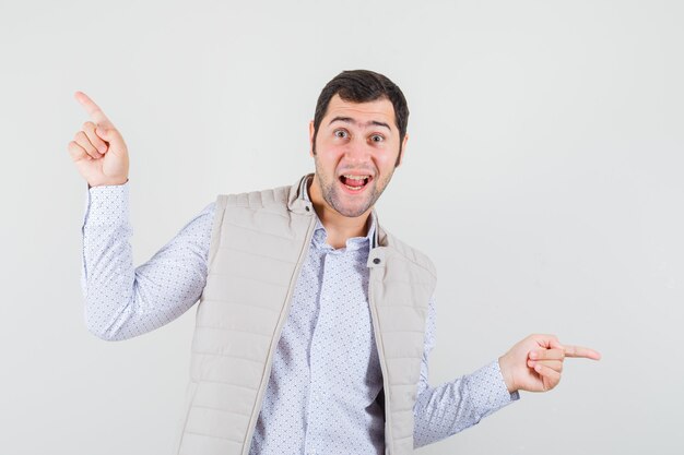 Jeune homme pointant des directions opposées avec l'index en veste beige et à l'optimiste. vue de face.