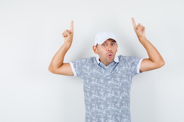 Jeune homme pointant les doigts vers le haut en t-shirt et casquette et à la troublé