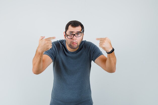 Jeune homme pointant sur elle-même en t-shirt gris et à la confusion