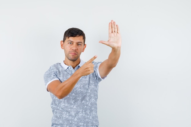 Jeune homme pointant sur le geste de refus en t-shirt et à la sérieuse