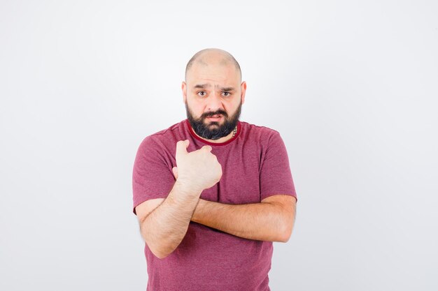 Jeune homme pointant sur lui-même en t-shirt rose et ayant l'air confus, vue de face.