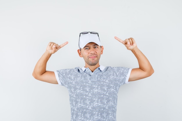 Jeune homme pointant sur des lunettes sur le chapeau en t-shirt et casquette et à la bonne humeur