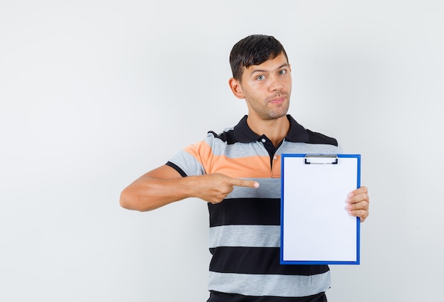 Jeune homme pointant sur le presse-papiers en t-shirt et à la prudence