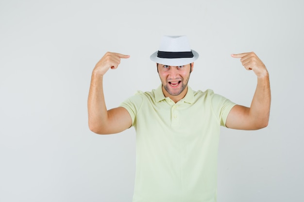 Jeune homme pointant sur son chapeau en t-shirt et à la joyeuse