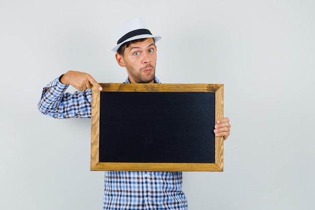 Photo gratuite jeune homme pointant sur tableau noir en chemise à carreaux