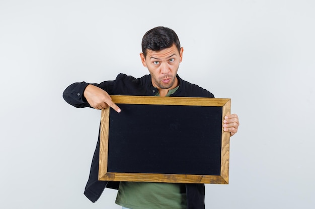 Jeune homme pointant sur tableau noir en t-shirt, vue de face de la veste.