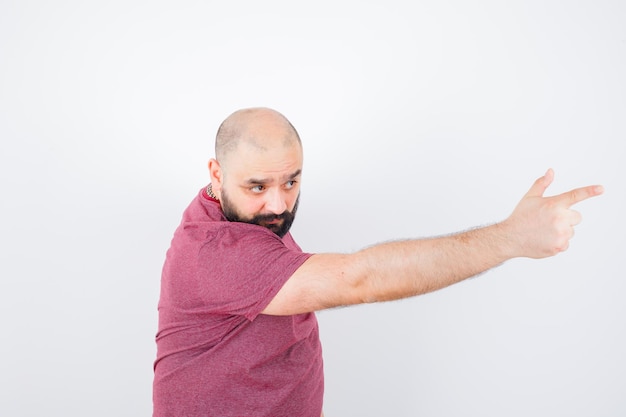 Jeune homme pointant vers l'avant en t-shirt rose, vue de face.