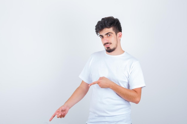 Jeune homme pointant vers le bas en t-shirt blanc et à la confiance