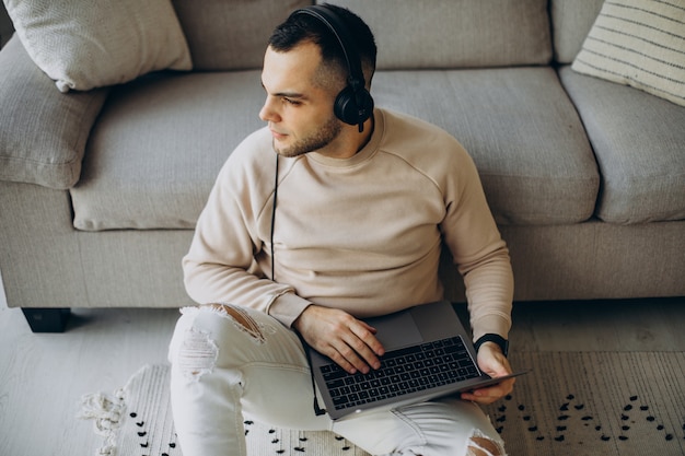 Jeune homme portant des écouteurs et utilisant un ordinateur à la maison