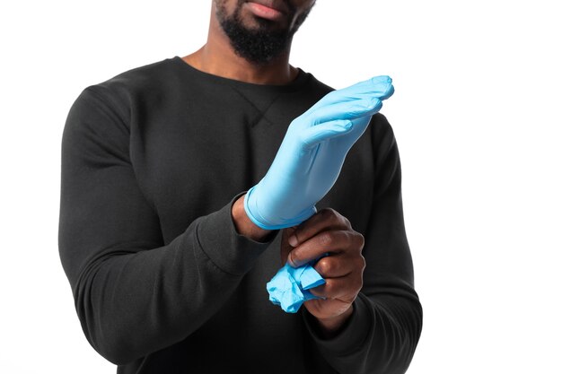 Jeune homme portant des gants de protection sur mur blanc