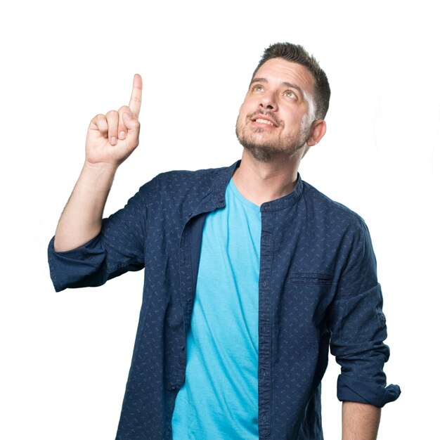 Jeune homme portant une tenue bleue. Pointant vers le haut avec son doigt.