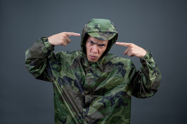 Photo gratuite le jeune homme porte un imperméable de camouflage et montre différents gestes.