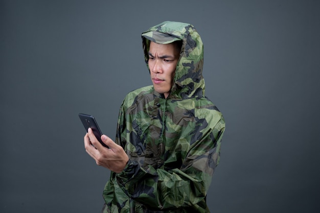 Le jeune homme porte un imperméable de camouflage et montre différents gestes.