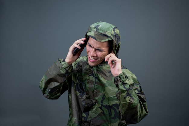 Le jeune homme porte un imperméable de camouflage et montre différents gestes.