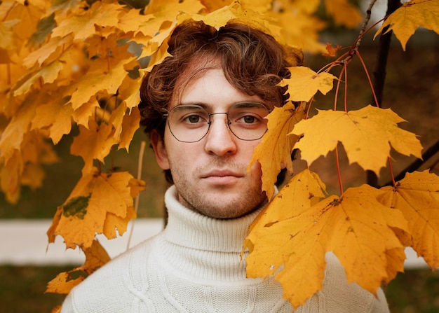 Jeune homme posant dans les feuilles d'automne