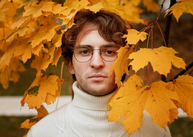 Jeune homme posant dans les feuilles d'automne