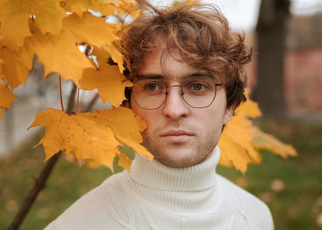 Jeune homme posant dans les feuilles d'automne