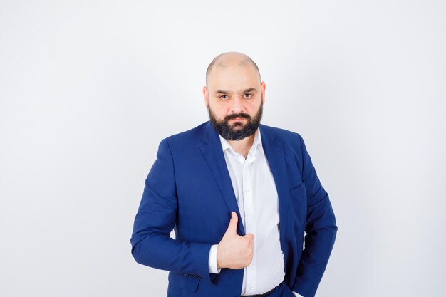 Jeune homme posant debout en chemise blanche, veste et l'air confiant. vue de face.