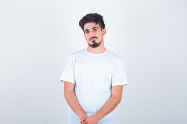 Jeune homme posant debout en t-shirt et ayant l'air confiant