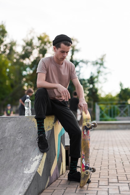 Photo gratuite jeune homme, poser, à, skateboard