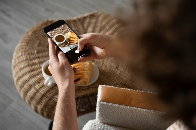 Jeune homme prenant une photo de son petit-déjeuner à l'aide de son smartphone