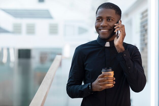 Jeune homme prêtre parlant sur smartphone