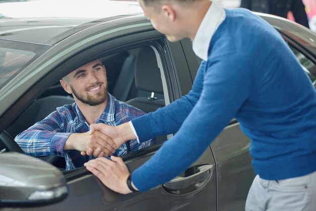 Jeune homme en pull bleu aidant un ami à choisir un véhicule