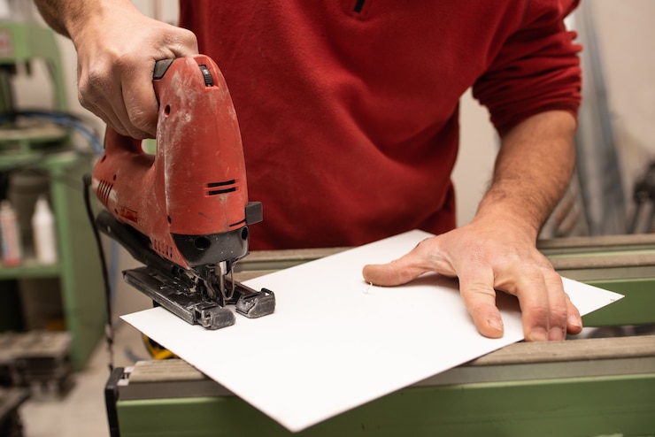 Photo gratuit jeune homme avec un pull rouge faisant quelque chose avec des outils industriels