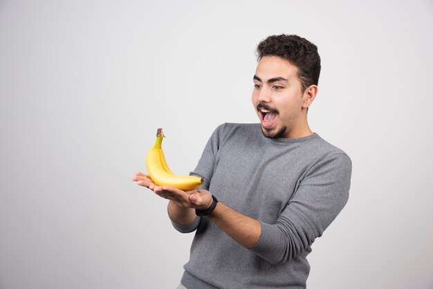 Jeune homme regardant la banane sur fond gris.