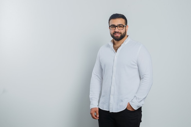 Jeune homme regardant la caméra en chemise blanche, pantalon et beau