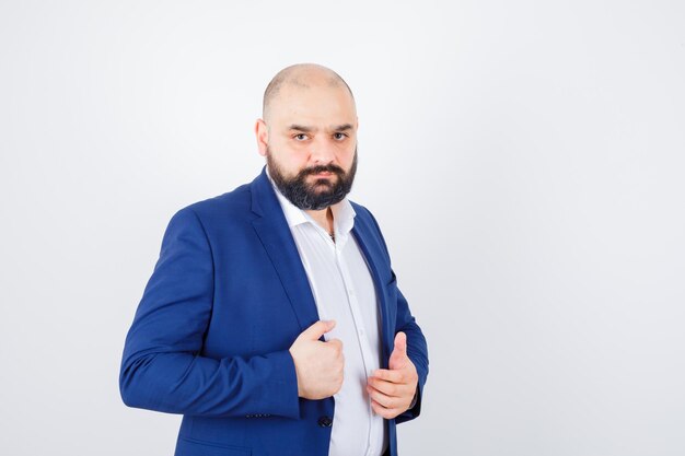 Jeune homme regardant la caméra tout en posant en chemise blanche, veste et élégant. vue de face.