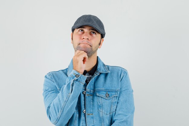 Jeune homme regardant en casquette, t-shirt, veste et à la pensif.