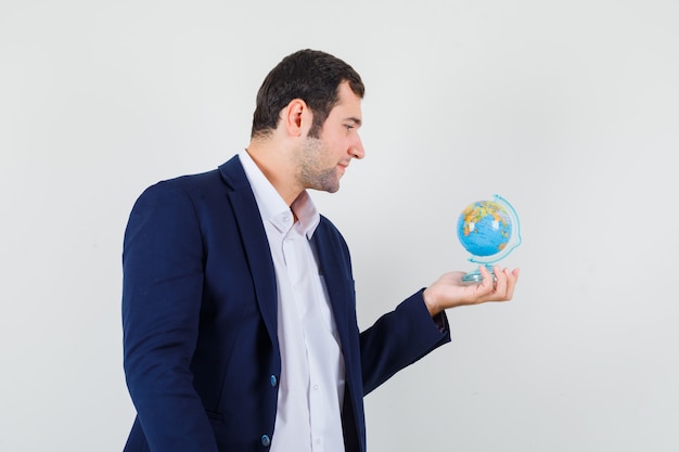 Jeune Homme Regardant Le Globe De L'école En Chemise Et Veste Et à La Pensif