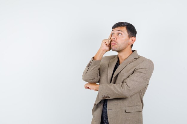 Jeune homme regardant loin en veste marron grisâtre et à la réflexion. vue de face. espace libre pour votre texte