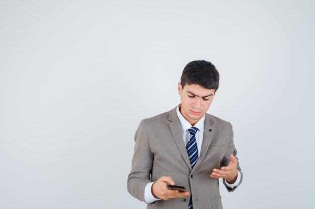 Jeune homme regardant le téléphone, tendant la main vers lui en costume formel
