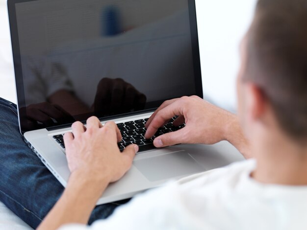 Jeune homme regarde dans l'ordinateur portable de près