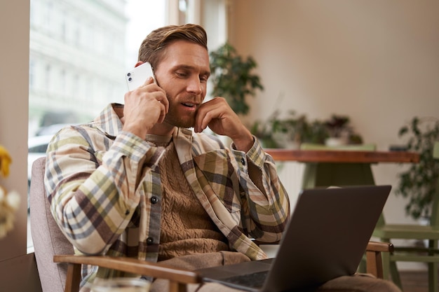 Un jeune homme regarde le site Web sur son ordinateur portable et appelle pour se renseigner sur le produit, commander quelque chose en ligne.