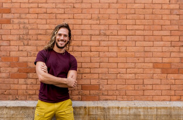 Jeune homme, regarder appareil-photo, à, mur brique