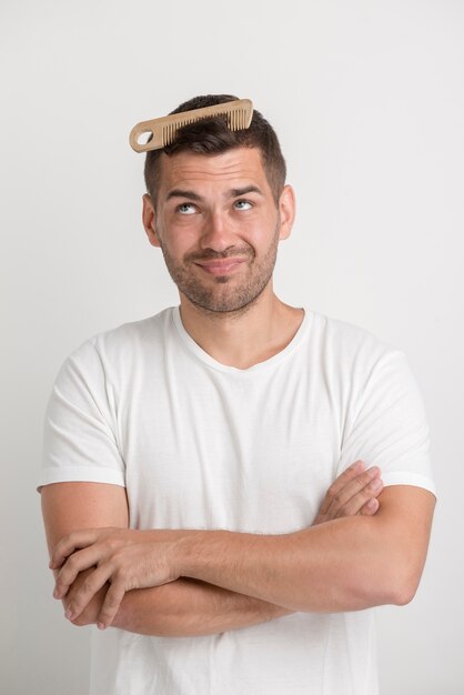 Jeune homme, regarder, peigne, coincé dans cheveux, debout, contre, fond blanc