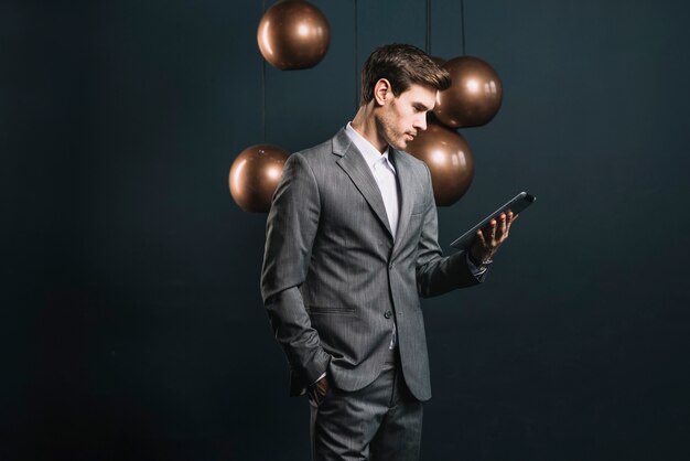 Jeune homme, regarder, tablette numérique, debout, devant, miroir profilé, rond, lustre cuivre