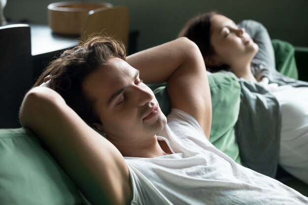 Jeune homme reposant sur un canapé confortable avec sa petite amie à la maison