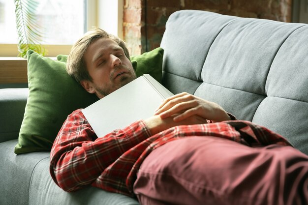 Jeune homme restant à la maison sur le canapé