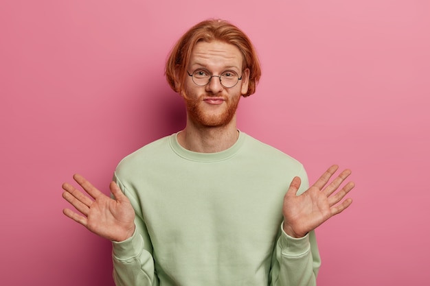 Photo gratuite un jeune homme rousse indifférent lève les paumes