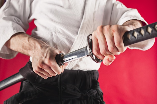 Photo gratuite le jeune homme s'entraîne à l'aïkido au studio avec un maître d'aïkido au sabre tirant une épée