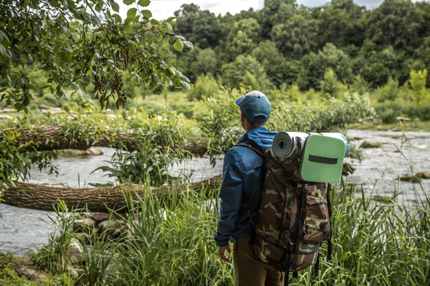 Jeune homme avec un sac à dos de randonnée traversant des lacs