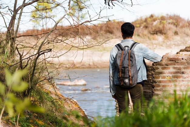 Jeune homme avec sac à dos en regardant le lac