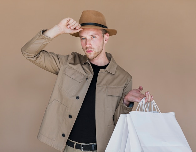 Jeune homme avec des sacs à provisions à la recherche de la caméra